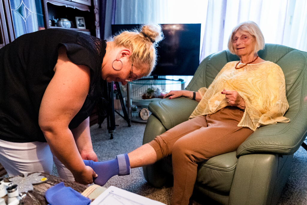 Pflegefachkraft von Janine's Pflegeteam bei der Behandlungspflege im Wohnzimmer