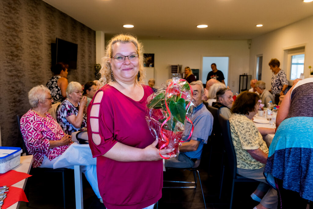 Mitarbeiterin von Janine's Pflegeteam mit Blumenstrauss bei einer Feier