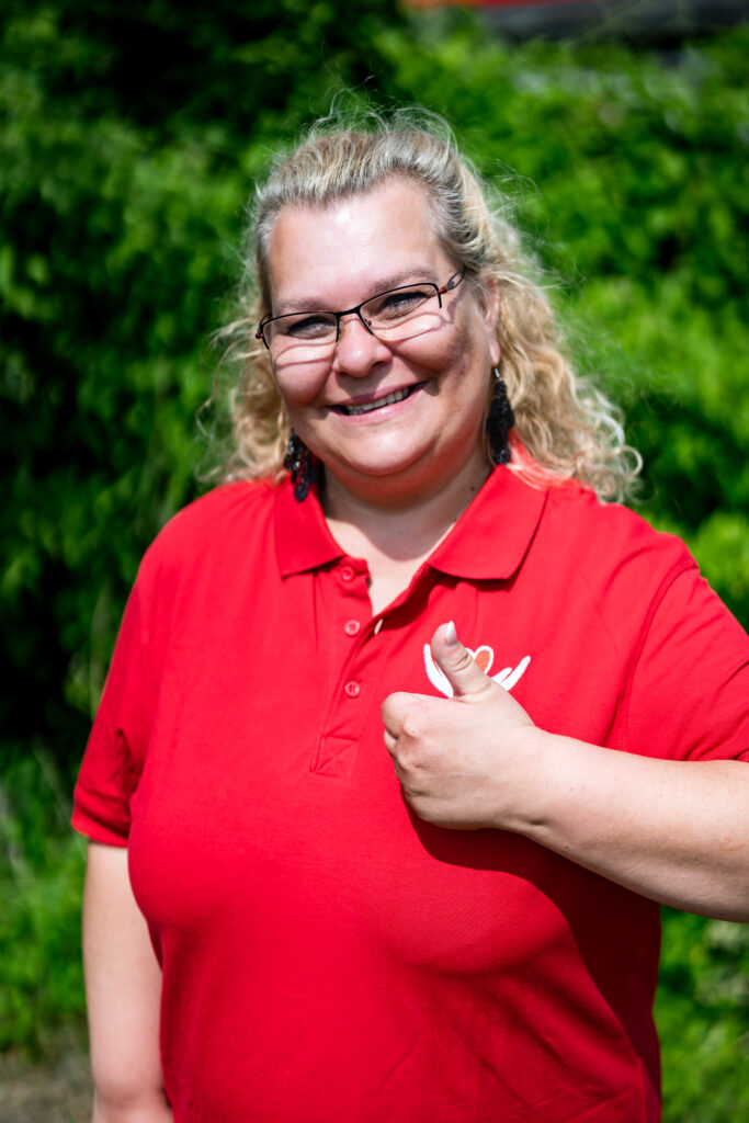 Mitarbeiterin von Janine's Pflegeteam im roten Poloshirt